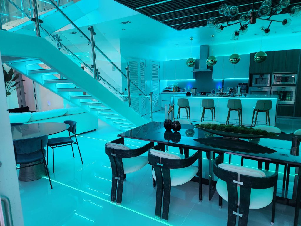 Modern kitchen and dining area with turquoise LED lighting.